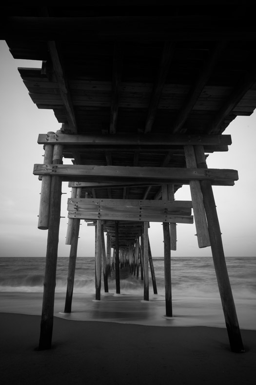 Black-and-white long exposure shot taken under the Avon Pier in Avon, North Carolina